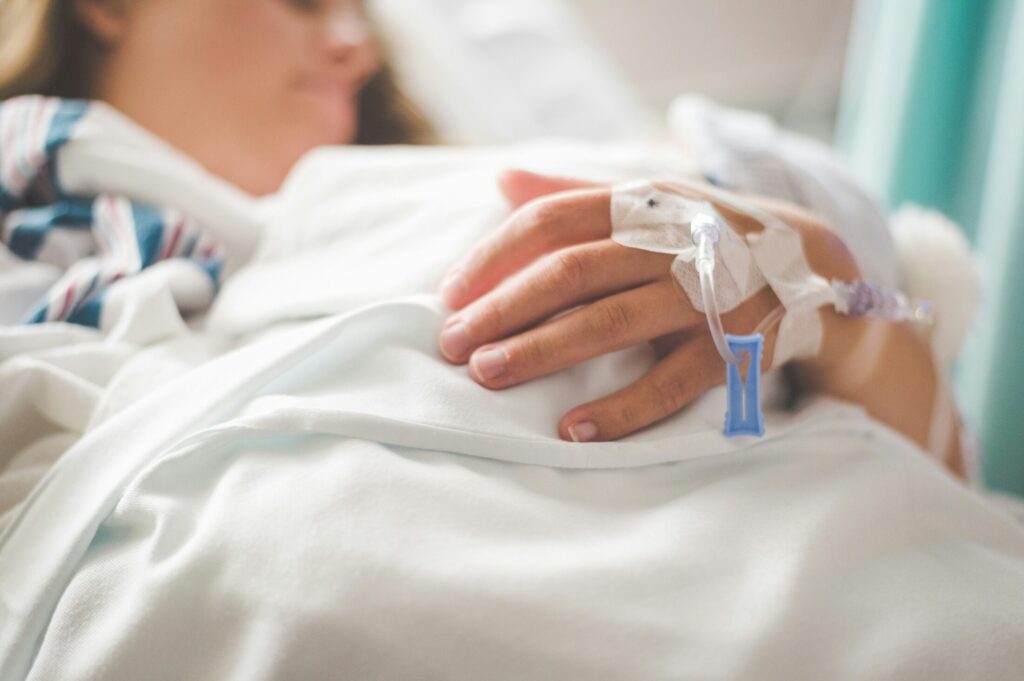 a woman laying on a hospital bed with an iv on her hand