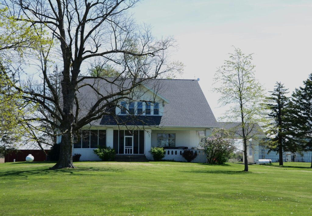 A white house with a large tree in front of it.
