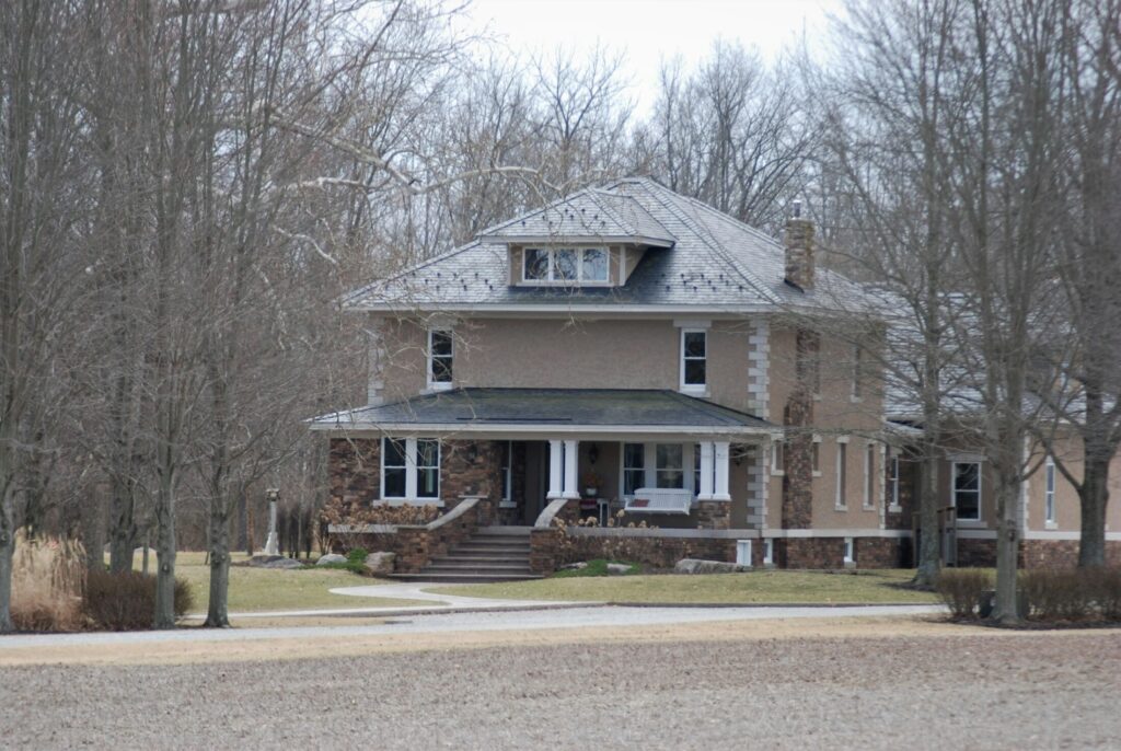 a large brown house surrounded by trees and grass.